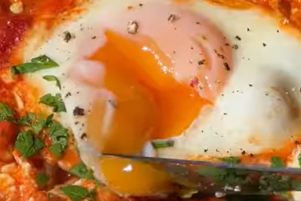 A hearty Smoky White Bean Shakshuka showcasing vibrant tomatoes, beans, and eggs, garnished with fresh parsley.