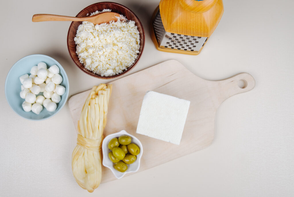 How to make cottage cheese with pickled olives on a wooden cutting board and string cheese.