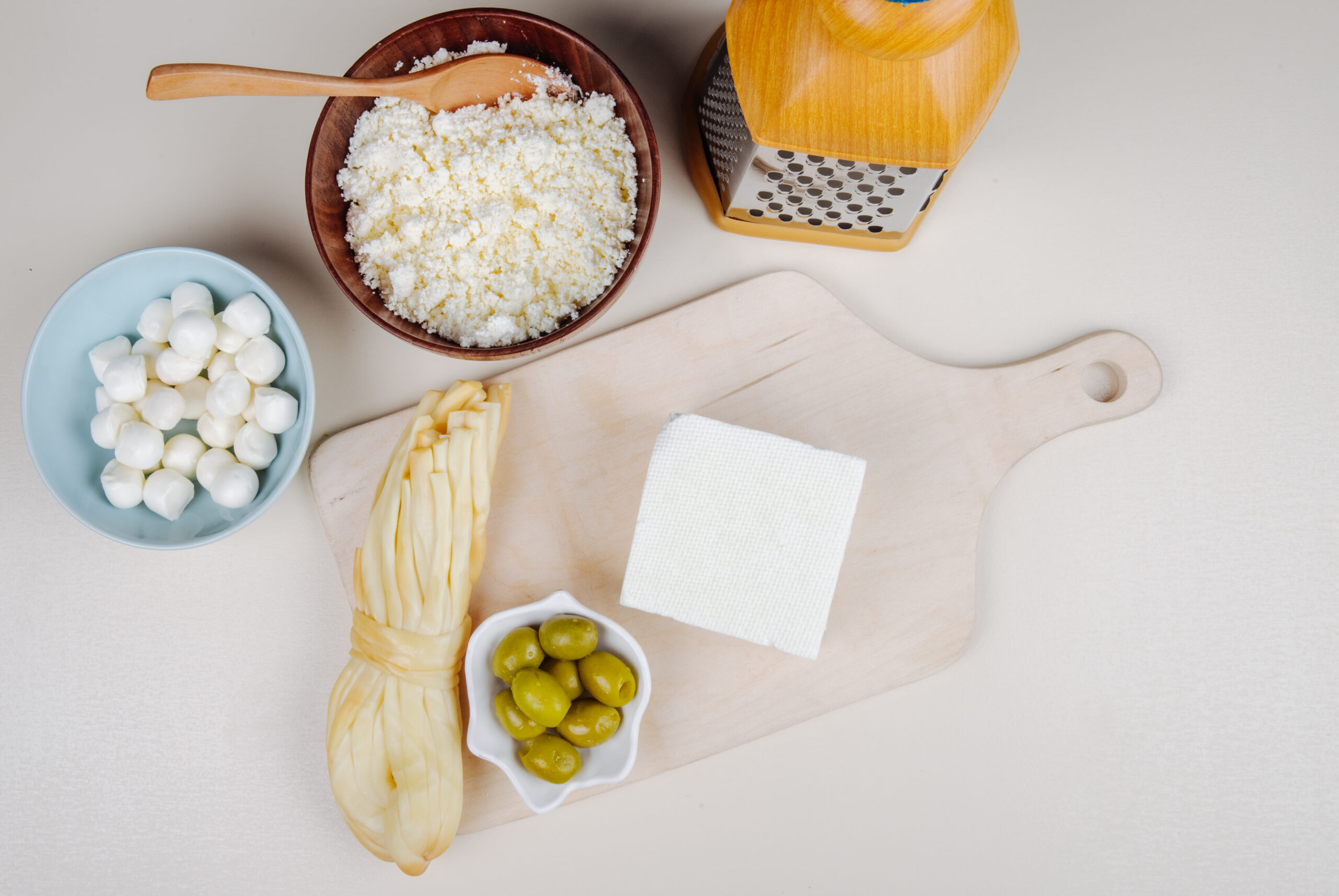 How to make cottage cheese with pickled olives on a wooden cutting board and string cheese.